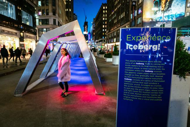 A girl in a pink coat in front of the entrance to Iceberg sculpture