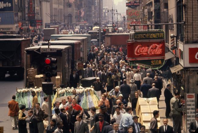 An overhead view of 7th Avenue crowded with trucks, pedestrians and full garment racks.
