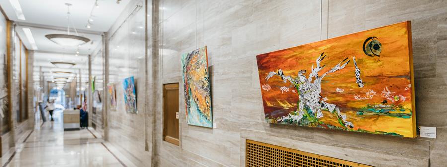 Colorful paintings hung in a long hallway lobby.