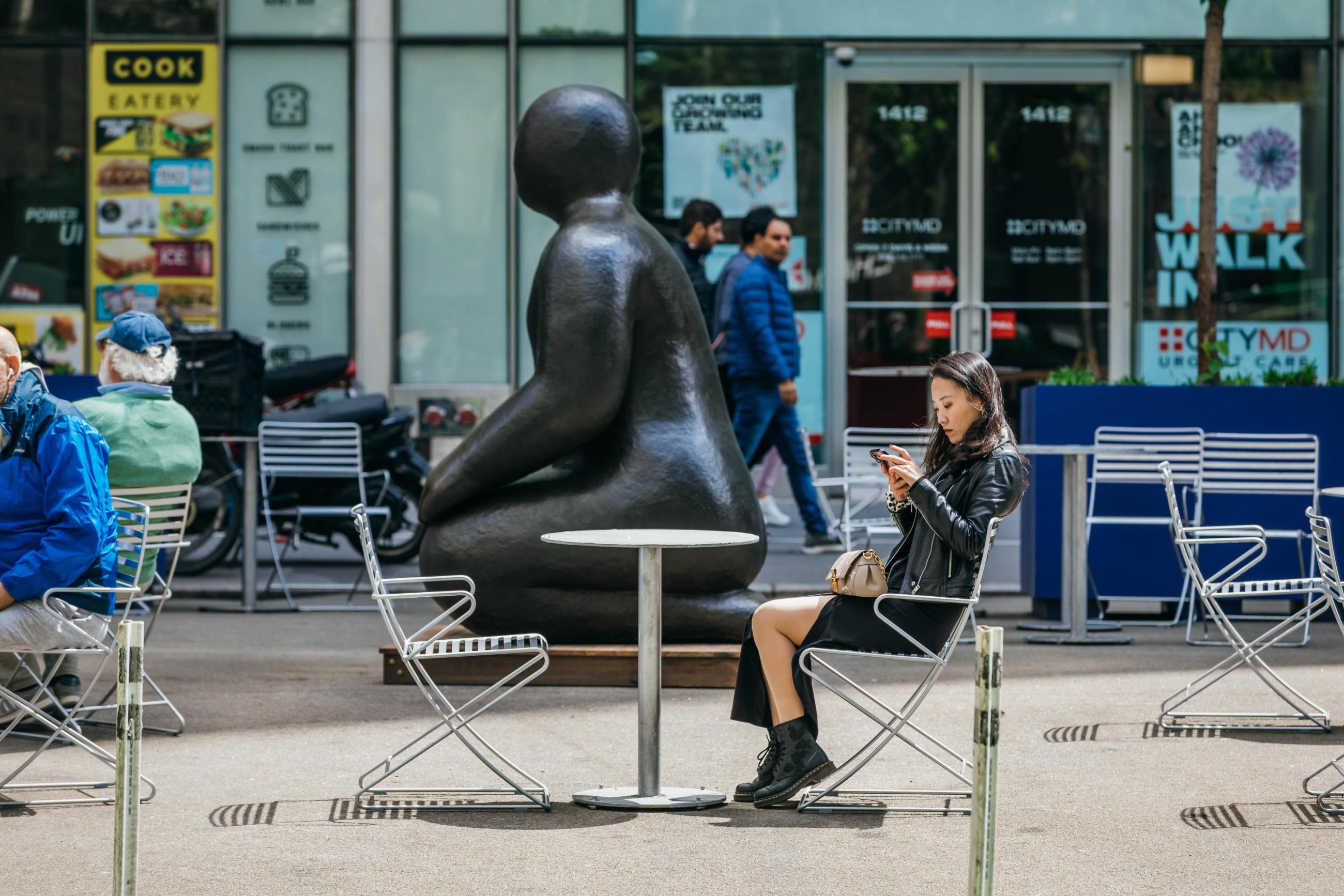 A large scltpture of a rounded kneeling figure on the broadway pedestrian plaza