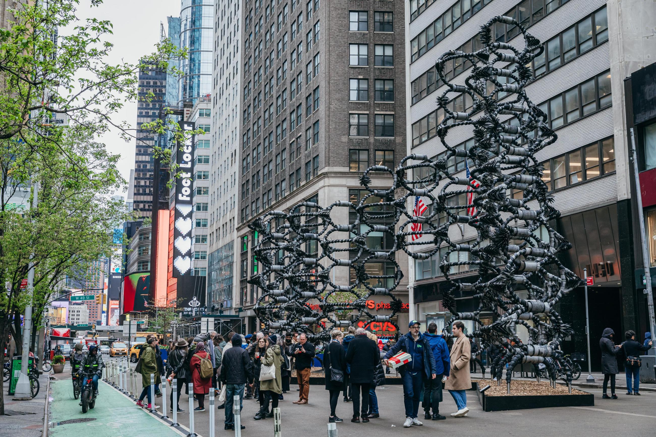 A crowd of people standing in front of the monumental Shaved Portion sculpture