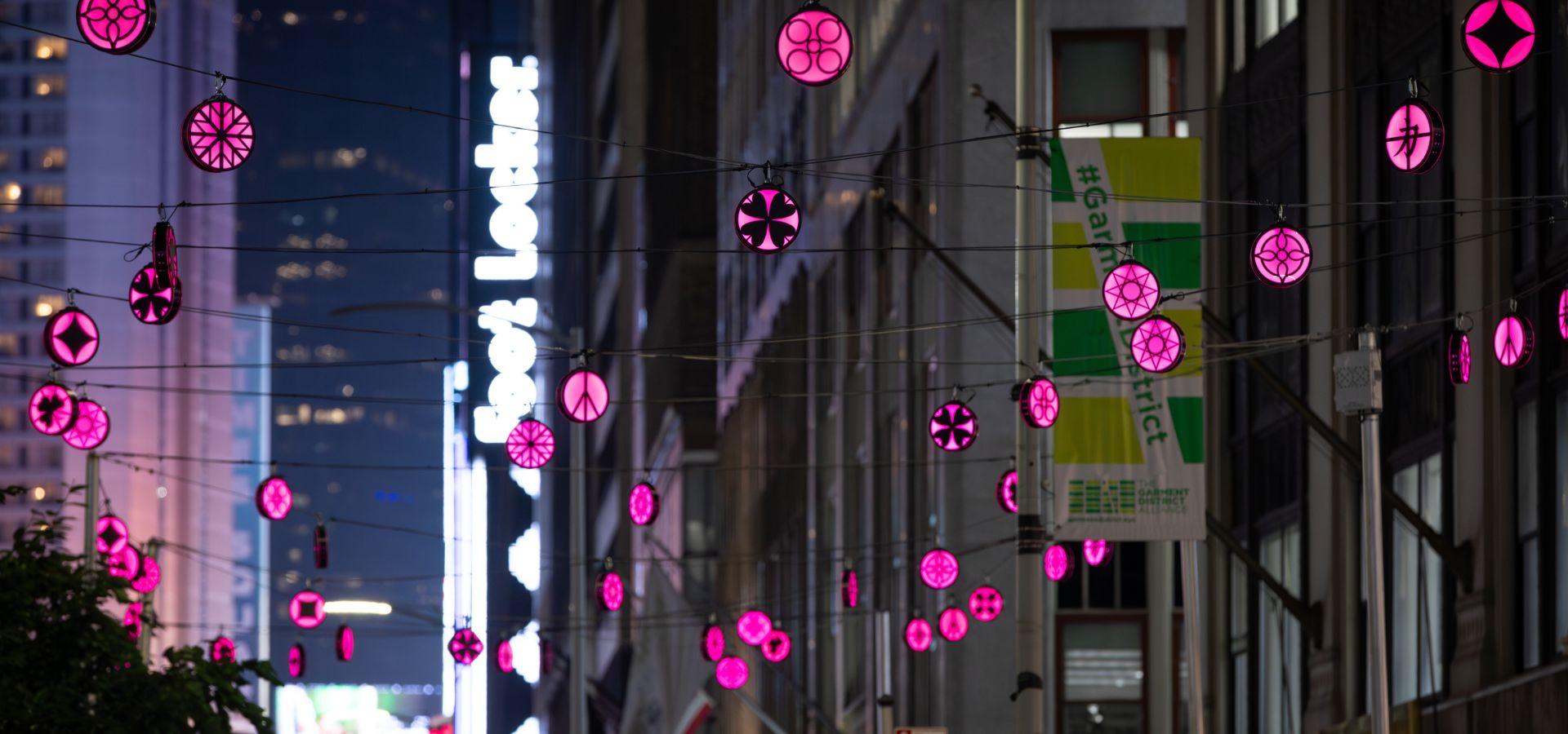 Magenta colored lanterns with symbols, hanging about the streets of Midtown