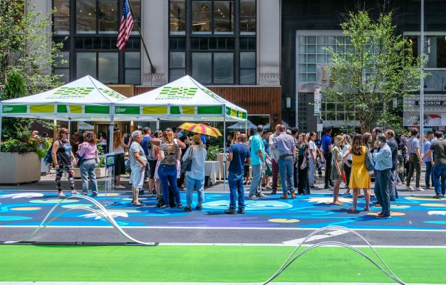 A group of people gathered on the plaza on mural painted on the street.