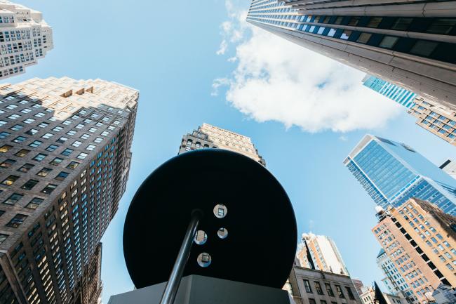 View up from the base of the Button & Needle sculpture with blue sky and surrounding skyscrapers