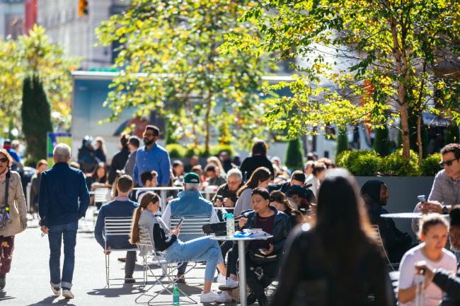 Plaza with people seated in chairs around table