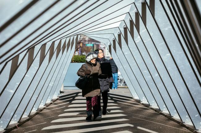 A pair of women inside the Iceberg sculpture with pattern on the ground created by the sun shining through the sculpture