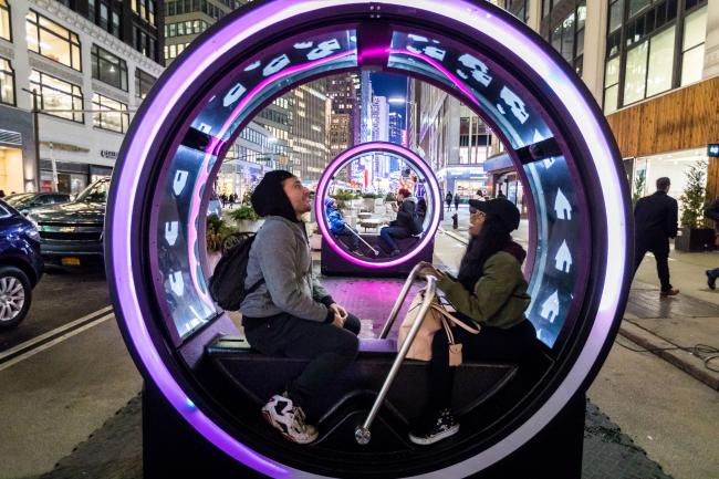 A couple sitting inside a lit-up LOOP sculpture at night