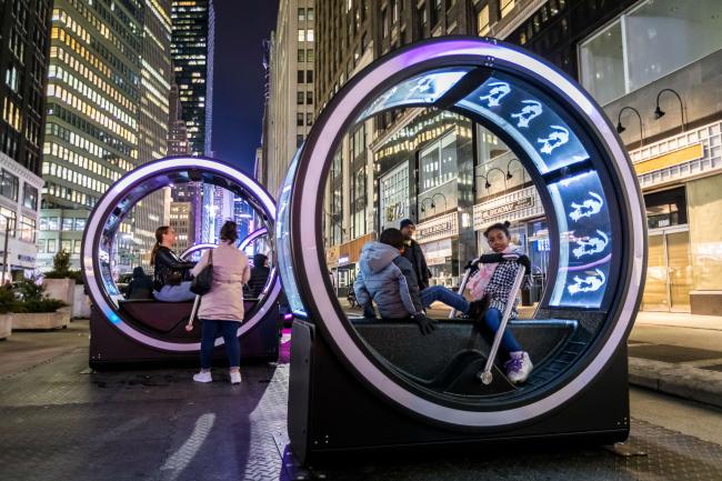 A pair of children inside a lit-up LOOP at night