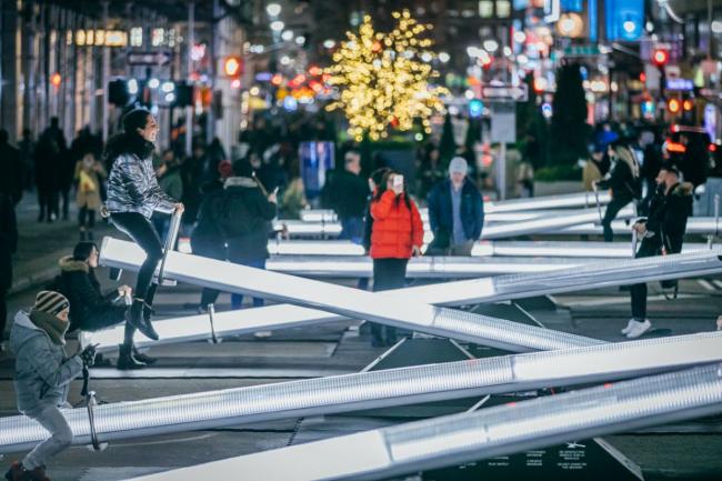 A row of lit up seesaws with a child in a red coat in the center taking a photo