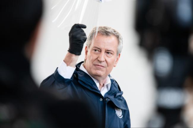 Mayor Bill deBlasio holding up a protective mask during a press conference