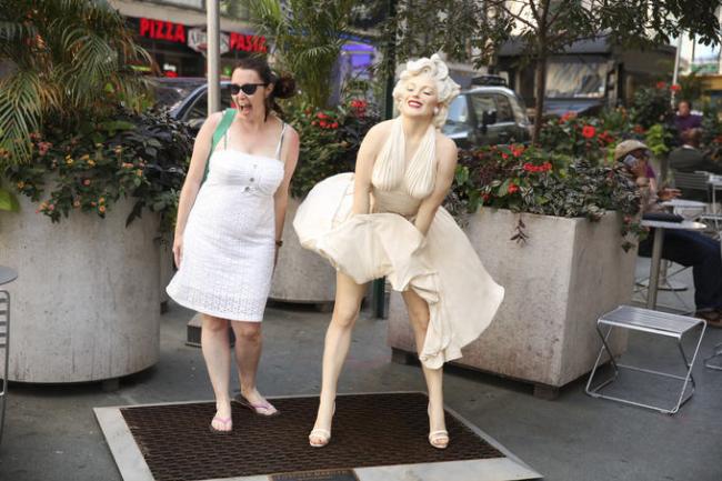 Woman standing next to a sculpture of Marilyn Monroe holding down her skirt