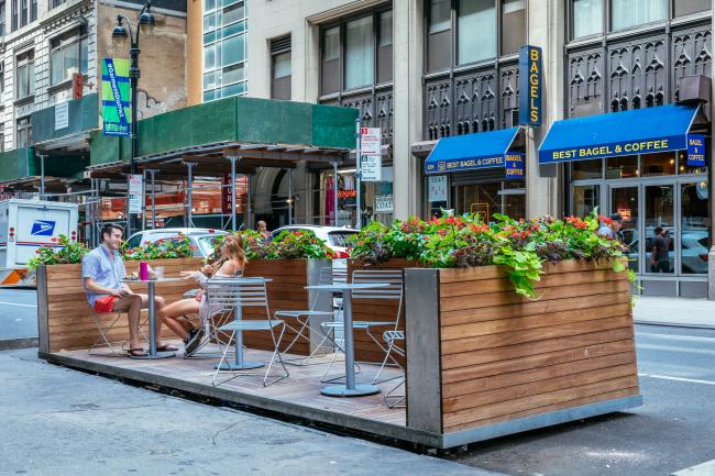 Wood and metal platform with tables and chairs atop it.