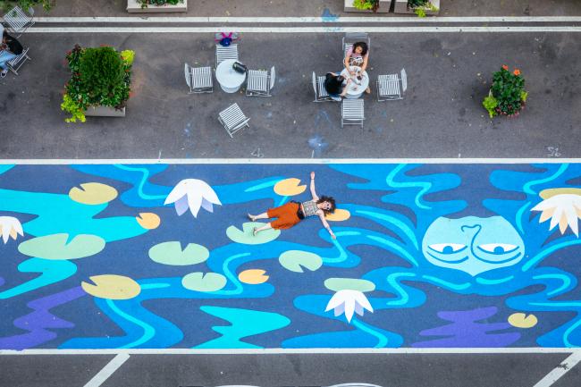 Overhead view of the artist lying atop her street mural