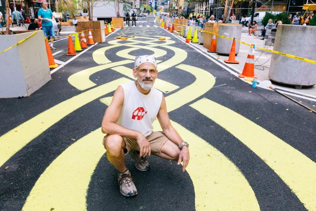 The artist crouched in front of his street mural