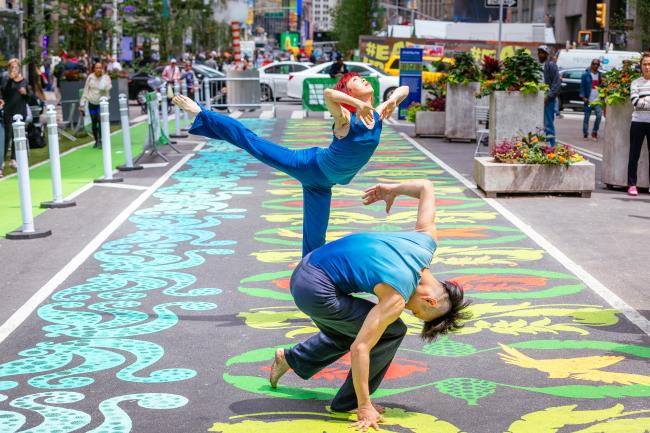 Two modern dancers performing atop a brightly-colored street mural.
