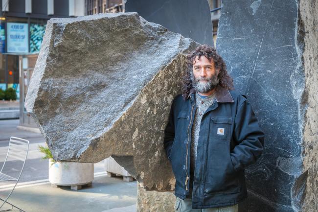 The artist in front of one of his stone sculptures