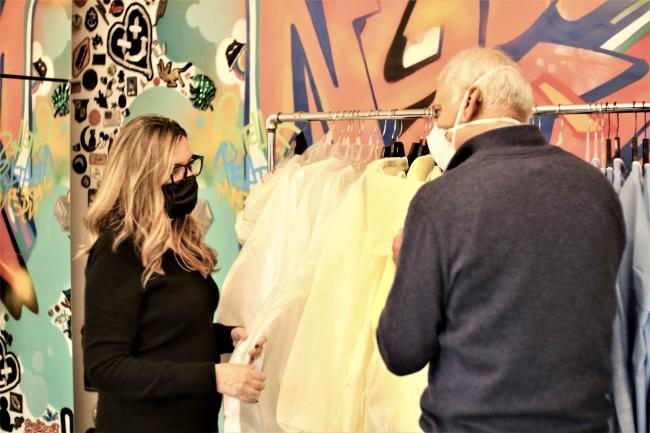 Two people wearing masks standing in front of a rack of clothing