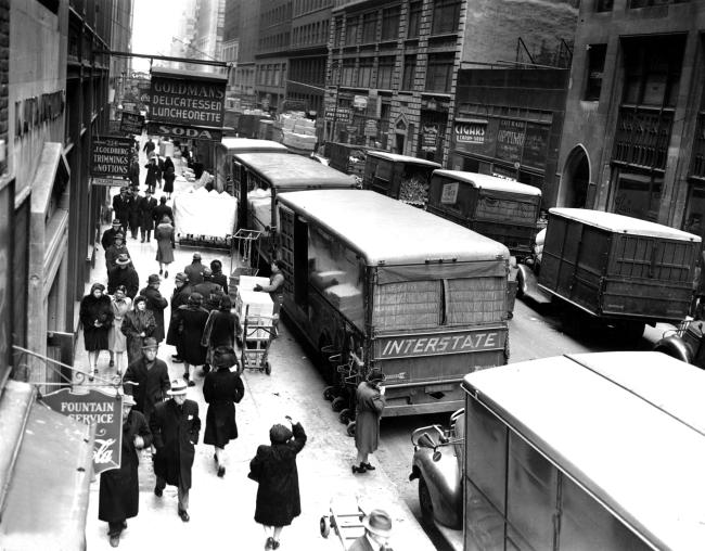 Overhead view of 8th Avenue with people on the sidewalk and the street full of trucks. Taken in November 1943.