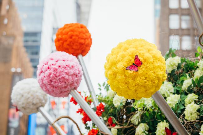 Close up of four pins created from metal rods and balls of yellow, orange, pink and white flowers.