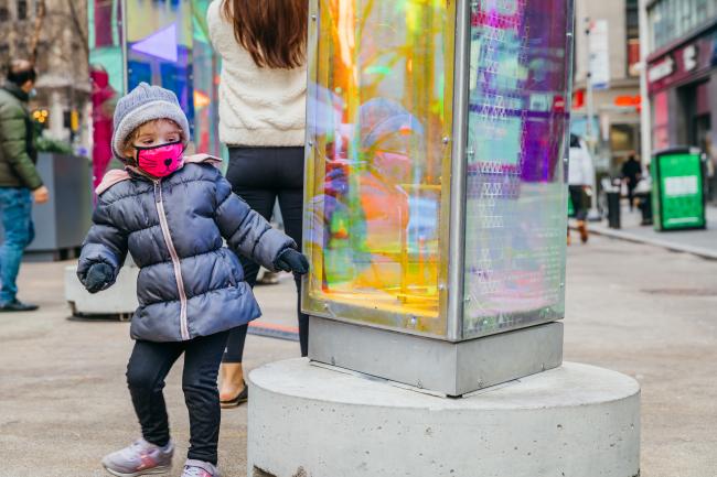 A young child in a winter coat next to a glass sculpture.