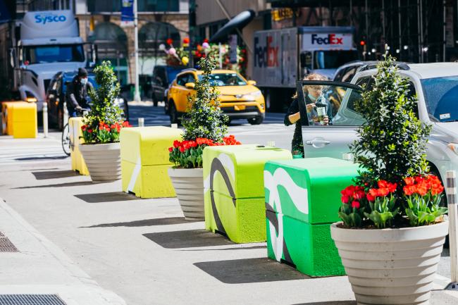 A row of brightly colored cubes in shades of green and yellow in a line along the curb