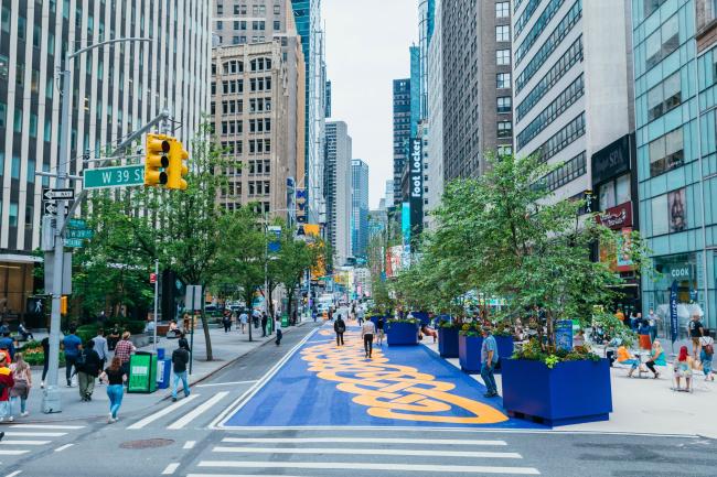 Looking up Broadway at the blue and orange mural, flanked by buildings on either side of the street.