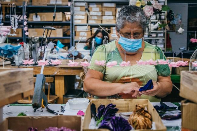 A woman at a table making fabric flowers.