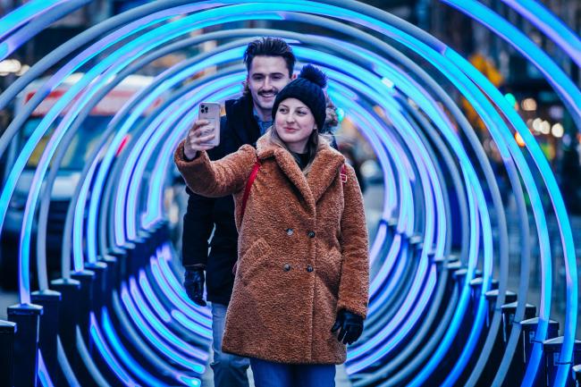 A couple posing for a selfie in a tunnel of blue rings