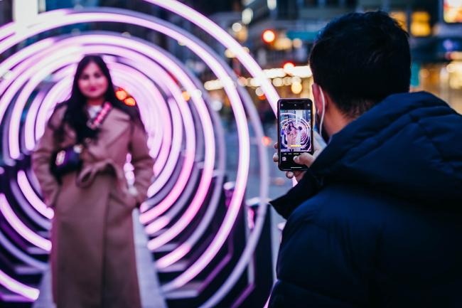 A Woman posing for a photo in the tunnel of lit up rings