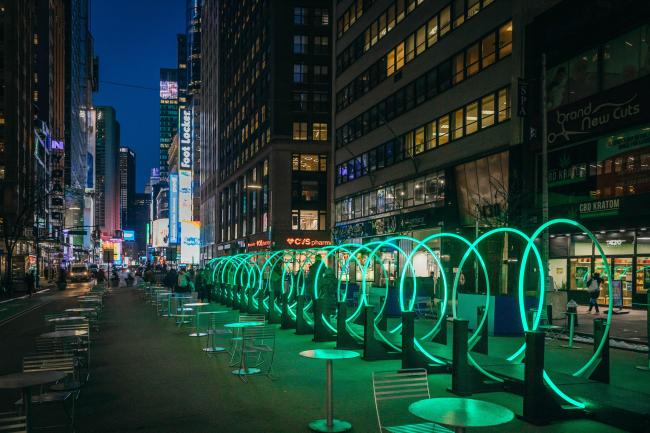A tunnel of rings lit up green with times square in the background.