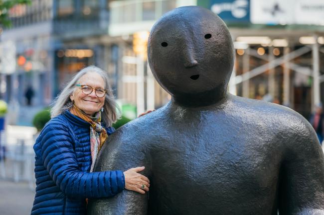 Artist Joy brown leaning on her sculpture, Kneeler