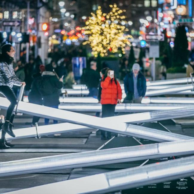 A row of lit up seesaws with a child in a red coat in the center taking a photo