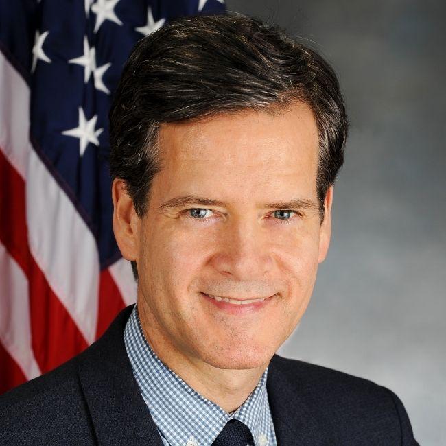 Brad Hoylman in a suit, smiling in front of an American flag. 