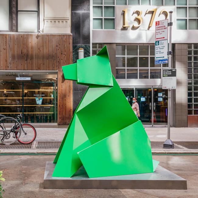 A green origami statue of a bear in front of a building