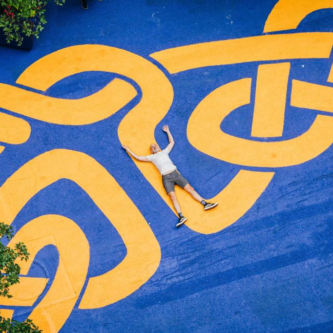 Steed Taylor laying out on his orange and blue braided mural