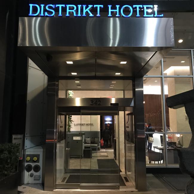 Distrikt Hotel at night with a light up sign