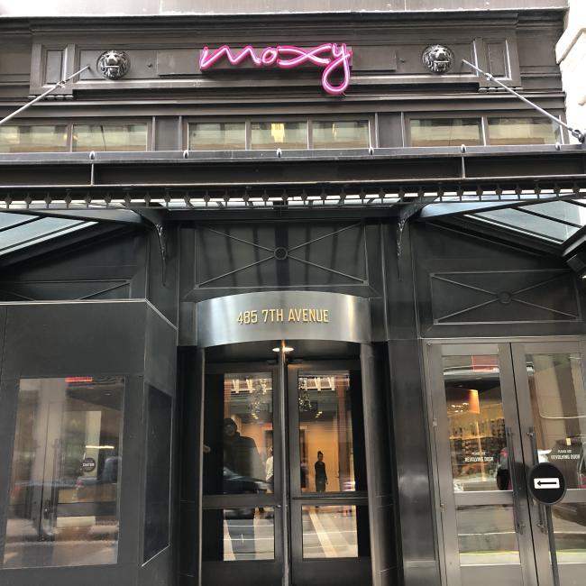 The illuminated and charming entrance to the Moxy Hotel