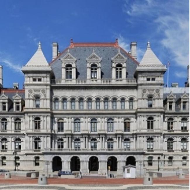 the outside of the NY State Sente building under a blue sky