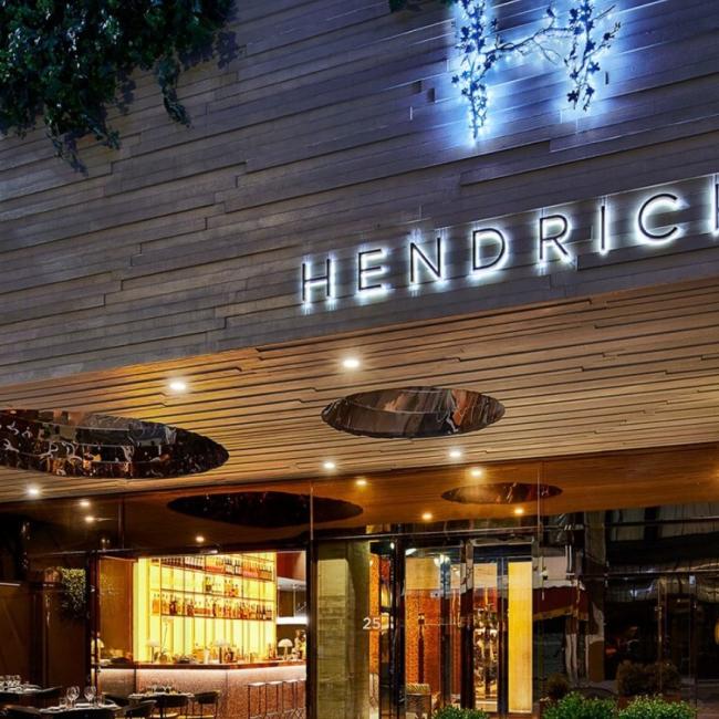 Exterior view of the Hendricks with tables and chairs in the courtyard and the bar visible through the window